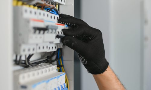 A male electrician works in a switchboard.